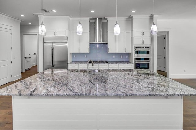 kitchen with stainless steel appliances, pendant lighting, a large island, and wall chimney range hood