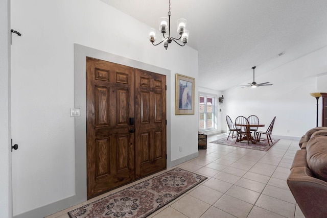 foyer with lofted ceiling, light tile patterned floors, and ceiling fan with notable chandelier