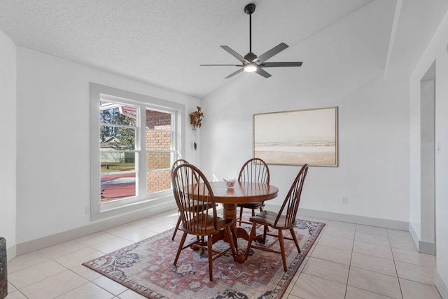 dining space featuring light tile patterned floors, vaulted ceiling, a textured ceiling, and ceiling fan