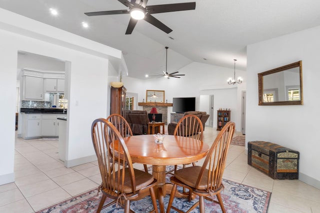 tiled dining space with ceiling fan with notable chandelier and vaulted ceiling