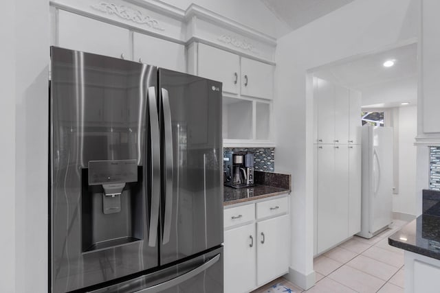 kitchen with stainless steel refrigerator with ice dispenser, light tile patterned flooring, white fridge, and white cabinets