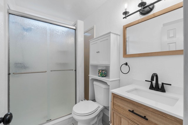 bathroom with vanity, a shower with door, and toilet