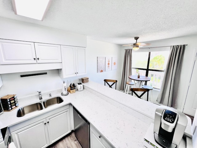 kitchen featuring sink, ceiling fan, white cabinetry, a textured ceiling, and stainless steel dishwasher