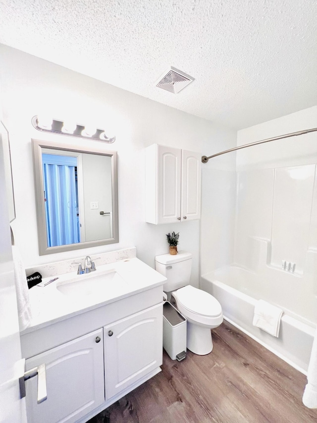 full bathroom featuring tub / shower combination, hardwood / wood-style floors, vanity, a textured ceiling, and toilet