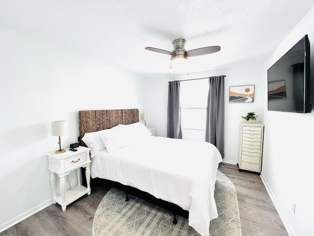 bedroom with hardwood / wood-style flooring, ceiling fan, and a textured ceiling