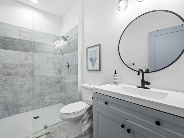 bathroom with vanity, toilet, and tiled shower