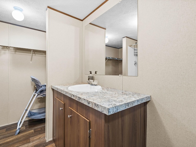 bathroom with vanity, hardwood / wood-style flooring, crown molding, and a textured ceiling