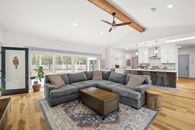 living room with vaulted ceiling with beams and light hardwood / wood-style floors