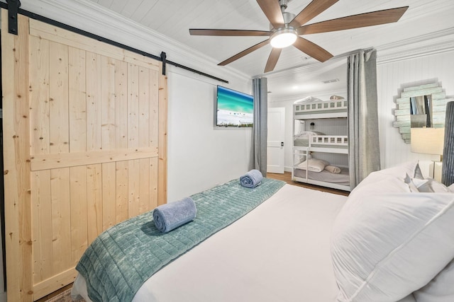 bedroom with wood-type flooring, ornamental molding, a barn door, and ceiling fan