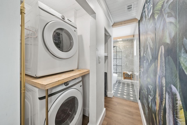 laundry room with stacked washer / drying machine and light hardwood / wood-style flooring