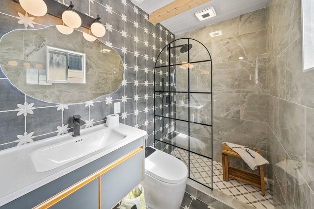 bathroom featuring tiled shower, vanity, toilet, and tile walls