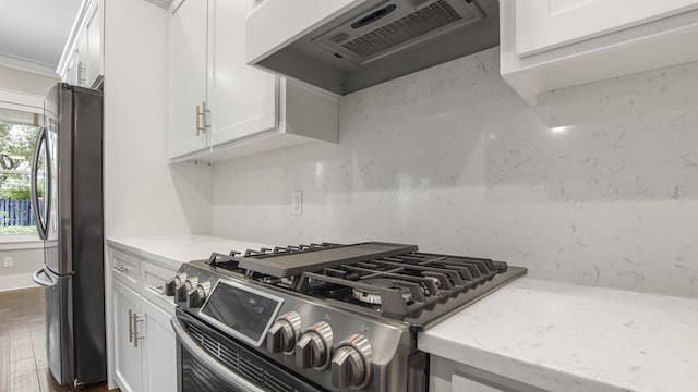 kitchen featuring premium range hood, light stone counters, appliances with stainless steel finishes, decorative backsplash, and white cabinets