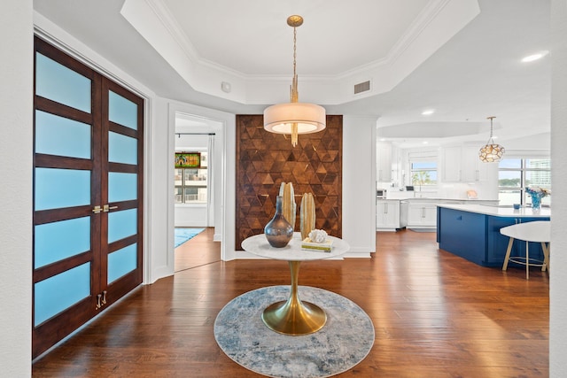 entrance foyer with a raised ceiling, ornamental molding, dark wood-type flooring, and french doors