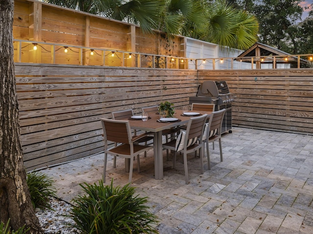 patio terrace at dusk featuring grilling area and exterior kitchen