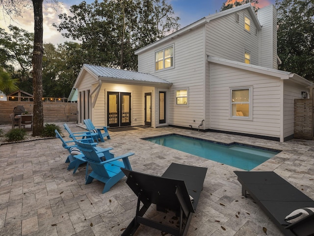 back house at dusk with a fenced in pool and a patio