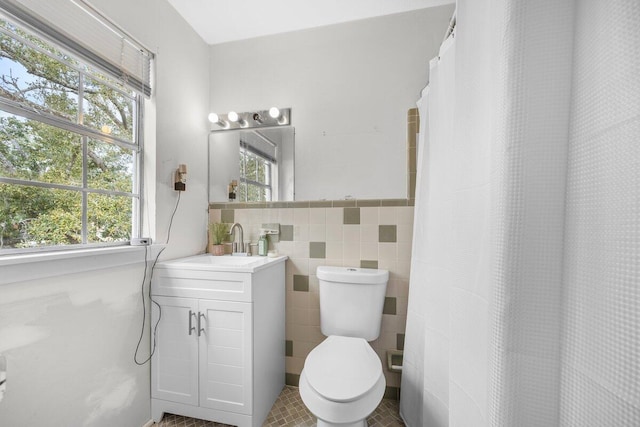 bathroom featuring vanity, a wealth of natural light, tile walls, and toilet