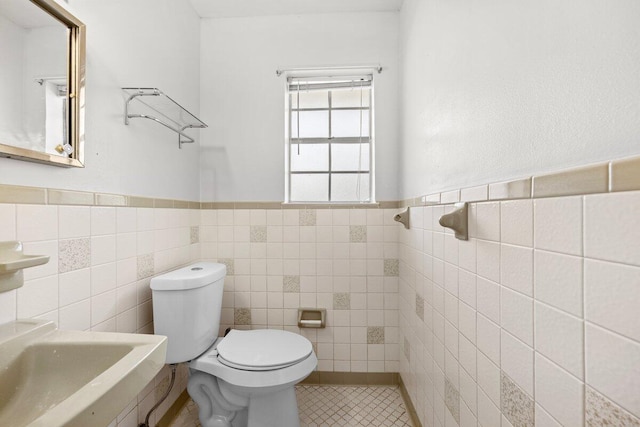 bathroom featuring toilet, tile patterned flooring, sink, and tile walls