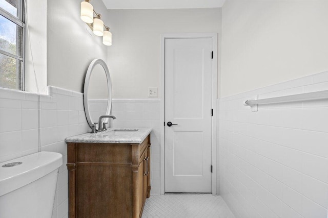 bathroom featuring vanity, tile walls, tile patterned floors, and toilet