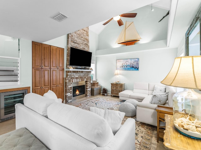 living room with heating unit, high vaulted ceiling, a brick fireplace, light hardwood / wood-style flooring, and ceiling fan