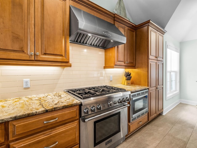 kitchen with backsplash, stainless steel appliances, light stone countertops, vaulted ceiling, and wall chimney exhaust hood