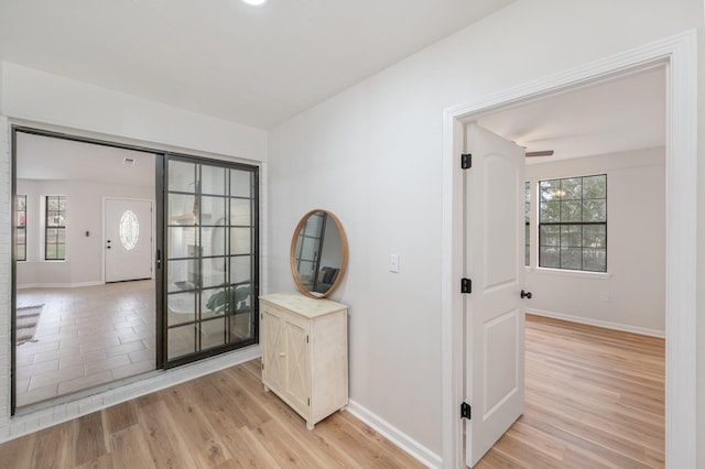hall with light wood-style flooring and baseboards
