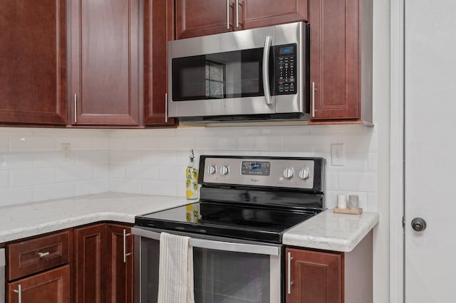 kitchen with stainless steel appliances, light stone countertops, and tasteful backsplash