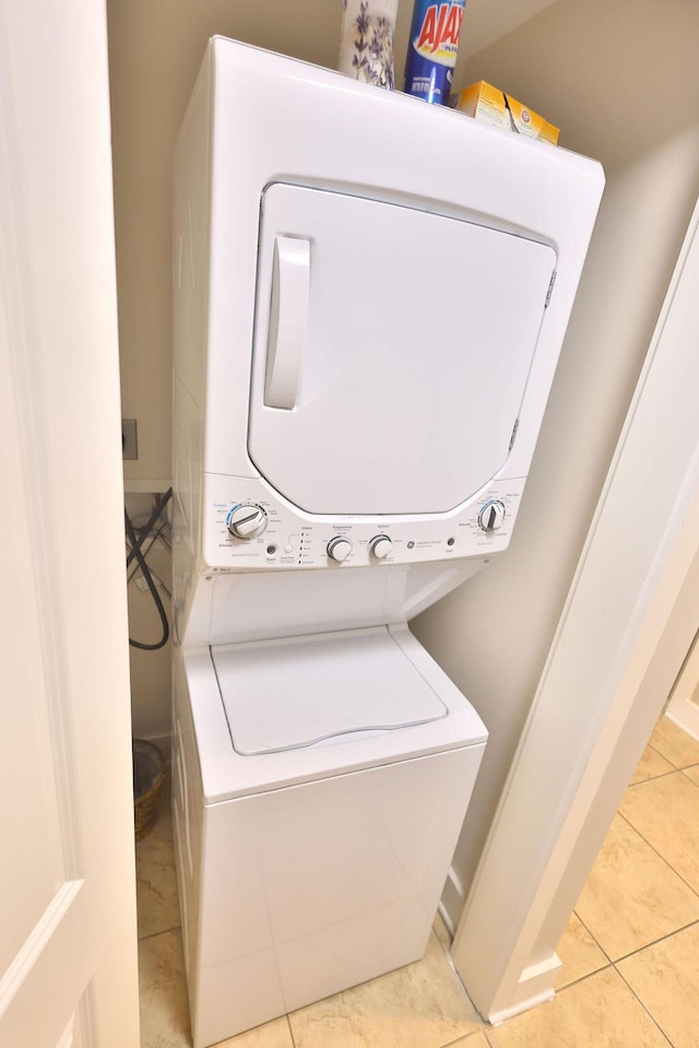 laundry area featuring light tile patterned floors and stacked washer / dryer