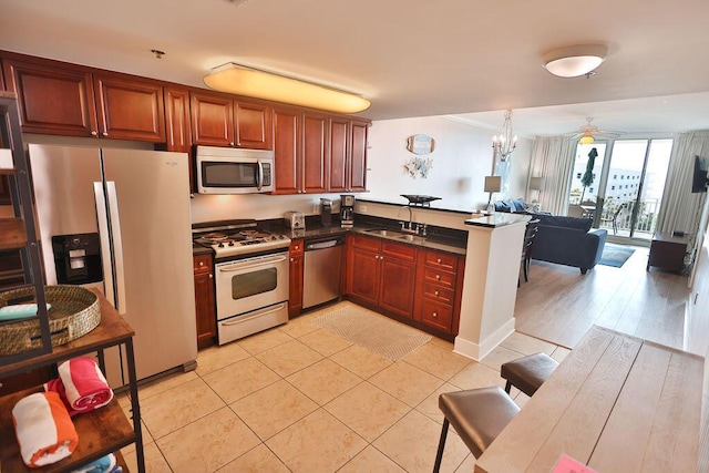 kitchen featuring appliances with stainless steel finishes, sink, hanging light fixtures, light tile patterned floors, and kitchen peninsula