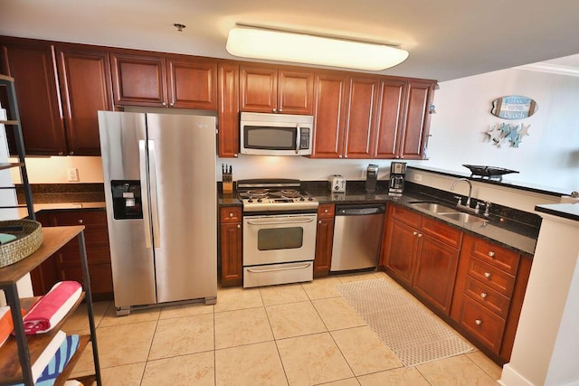 kitchen with dark stone countertops, sink, light tile patterned floors, and stainless steel appliances