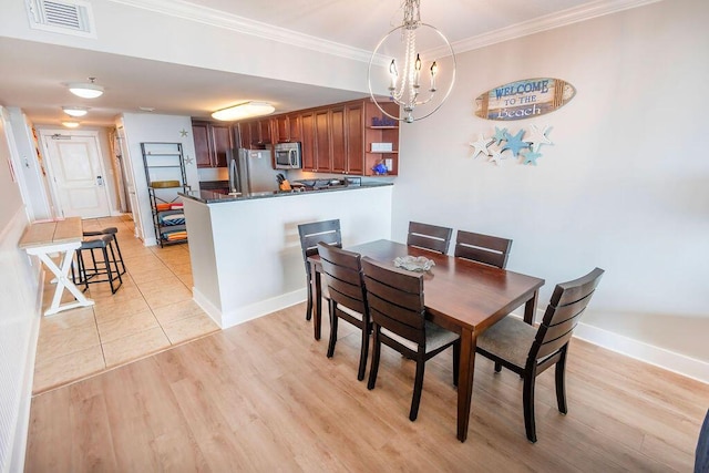 dining room with an inviting chandelier, crown molding, and light hardwood / wood-style flooring