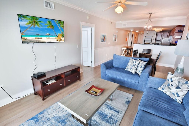 living room with crown molding, wood-type flooring, and ceiling fan with notable chandelier