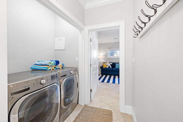 clothes washing area with light tile patterned floors, crown molding, and washer and dryer