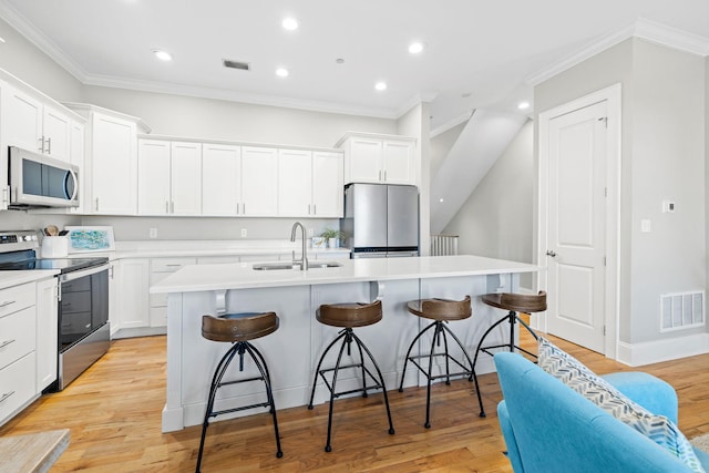 kitchen featuring sink, a breakfast bar area, stainless steel appliances, and an island with sink