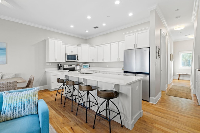 kitchen with white cabinetry, sink, stainless steel appliances, and a kitchen bar