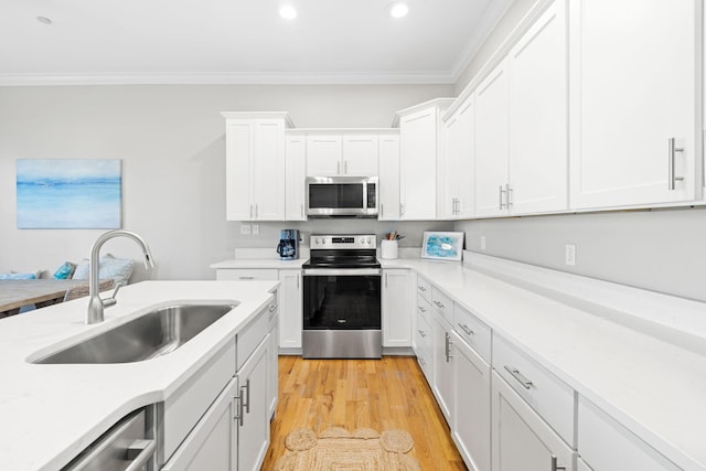 kitchen featuring sink, white cabinetry, stainless steel appliances, ornamental molding, and light wood-type flooring