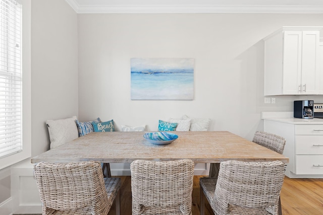 dining space with breakfast area, ornamental molding, and light hardwood / wood-style floors