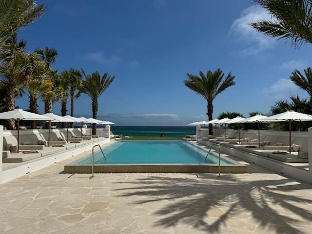 view of pool featuring a patio area and a water view