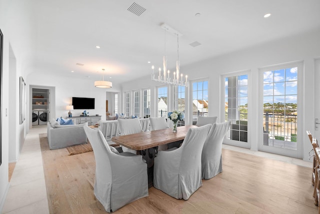 dining space featuring a chandelier, separate washer and dryer, and light wood-type flooring