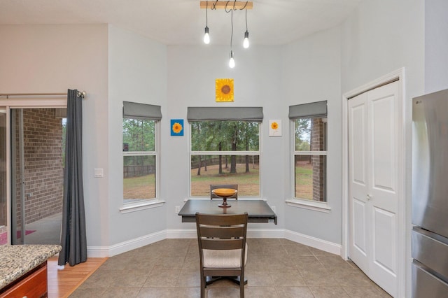 dining space featuring light tile patterned floors and a high ceiling