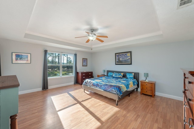 bedroom with a raised ceiling, ceiling fan, and light wood-type flooring