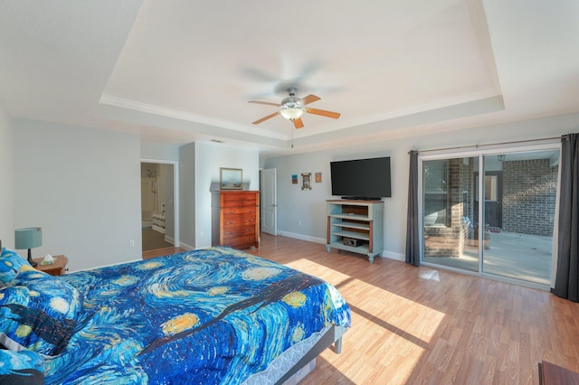 bedroom with access to exterior, wood-type flooring, and a raised ceiling