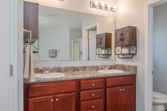 bathroom featuring vanity, toilet, and a shower with shower door