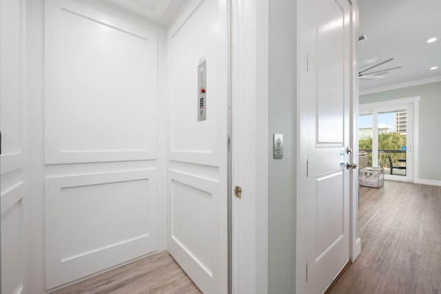 hall with ornamental molding and light hardwood / wood-style flooring