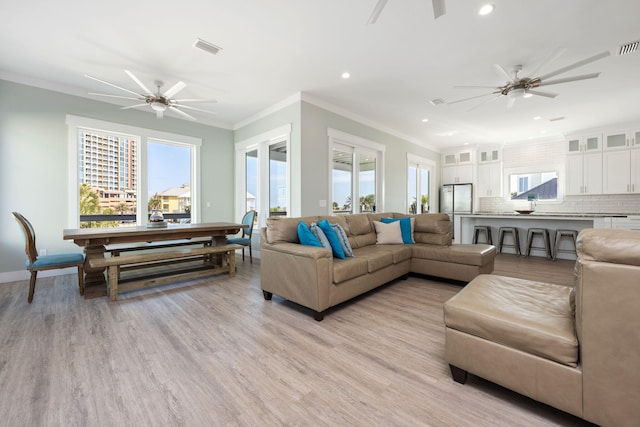 living room featuring crown molding, a healthy amount of sunlight, ceiling fan, and light wood-type flooring