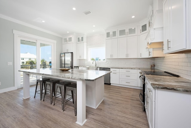 kitchen with white cabinetry, stainless steel appliances, a center island, and a kitchen bar