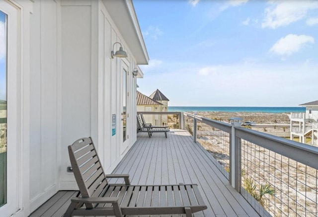 wooden deck with a water view and a view of the beach