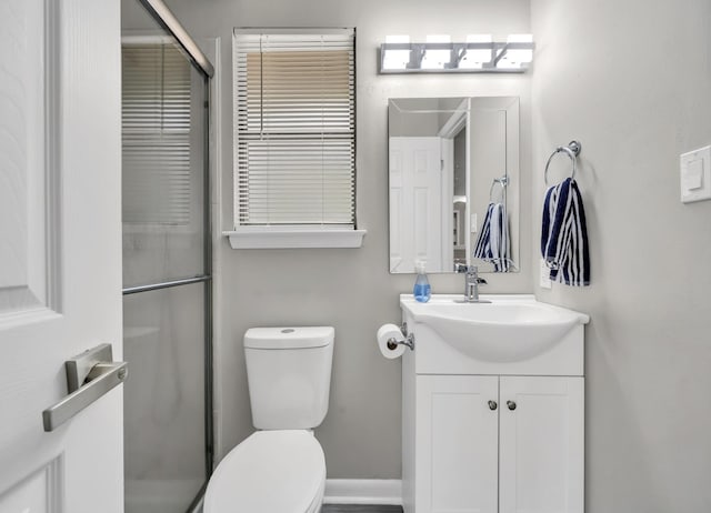 bathroom with vanity, toilet, and a shower with door