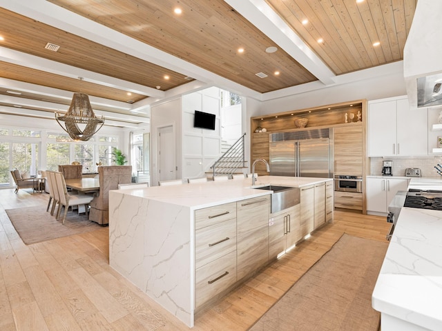 kitchen with light stone counters, sink, stainless steel appliances, and a spacious island