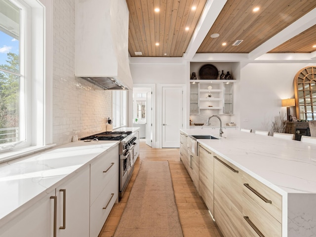 kitchen featuring premium range hood, a spacious island, sink, wood ceiling, and range with two ovens