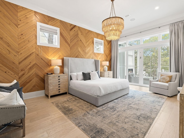 bedroom featuring wood walls, ornamental molding, access to outside, light hardwood / wood-style floors, and an inviting chandelier